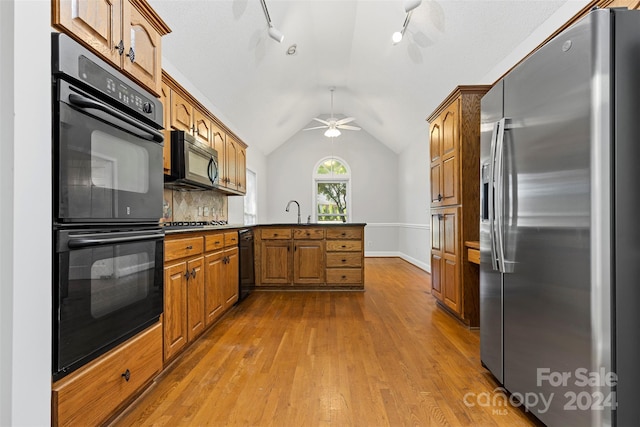 kitchen with black appliances, kitchen peninsula, ceiling fan, hardwood / wood-style flooring, and track lighting