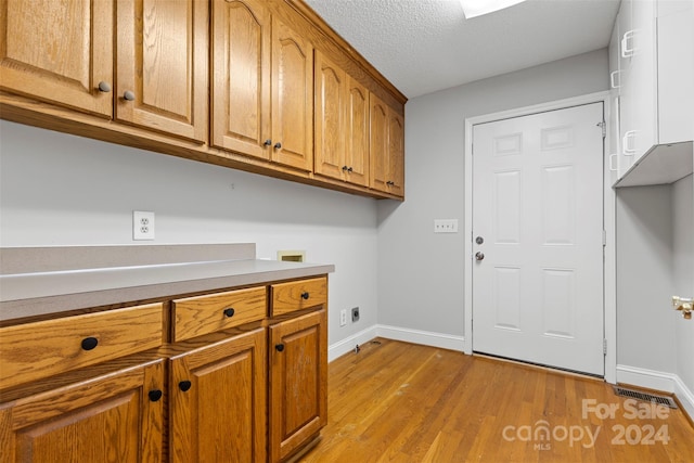 washroom with cabinets, washer hookup, a textured ceiling, electric dryer hookup, and light hardwood / wood-style floors