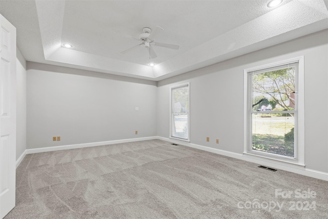 carpeted empty room featuring ceiling fan, a raised ceiling, and a textured ceiling