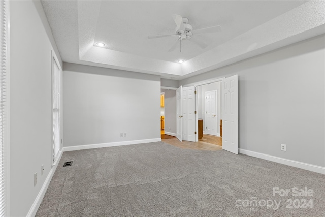 unfurnished bedroom featuring ceiling fan, a raised ceiling, carpet, and a textured ceiling