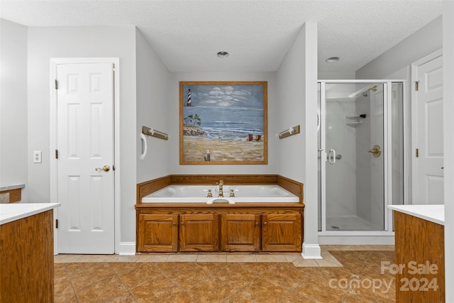 bathroom featuring vanity, tile patterned floors, independent shower and bath, and a textured ceiling