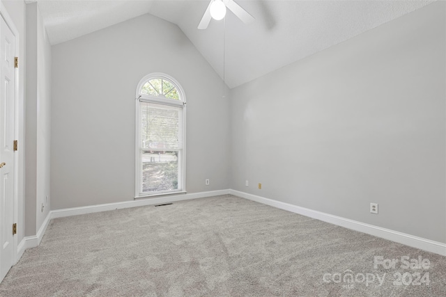 empty room featuring ceiling fan, vaulted ceiling, and carpet floors