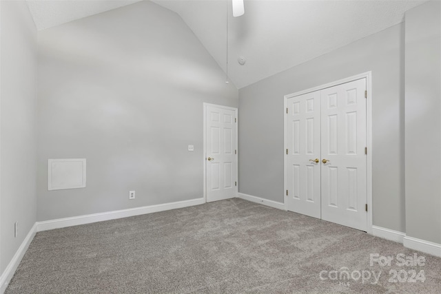 unfurnished bedroom featuring light carpet, a closet, high vaulted ceiling, and ceiling fan