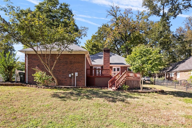 rear view of house with a wooden deck and a lawn