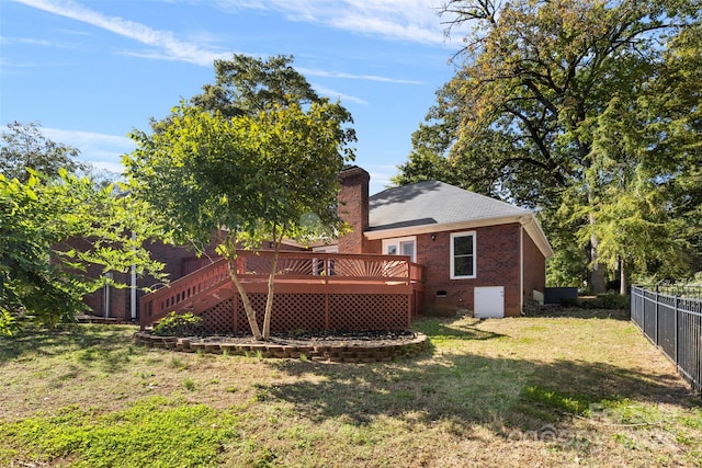 back of property with a deck and a yard