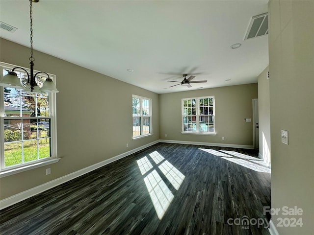 empty room with dark wood-type flooring and ceiling fan with notable chandelier