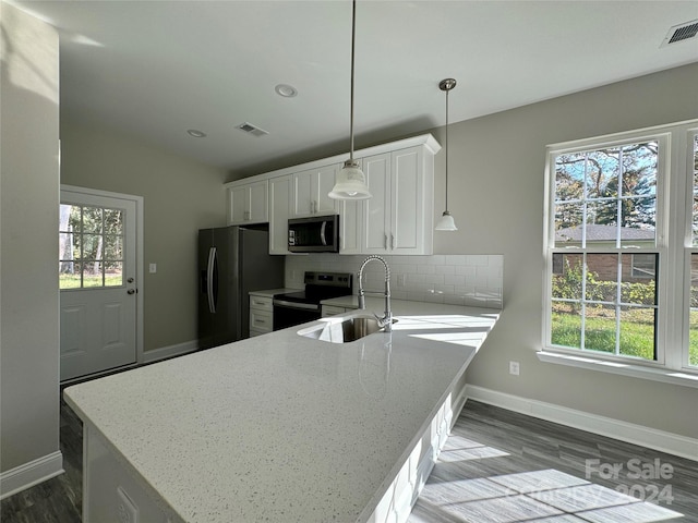 kitchen featuring kitchen peninsula, a healthy amount of sunlight, white cabinets, pendant lighting, and appliances with stainless steel finishes