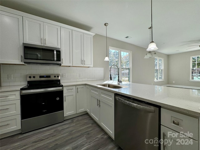 kitchen with appliances with stainless steel finishes, white cabinetry, sink, and a wealth of natural light