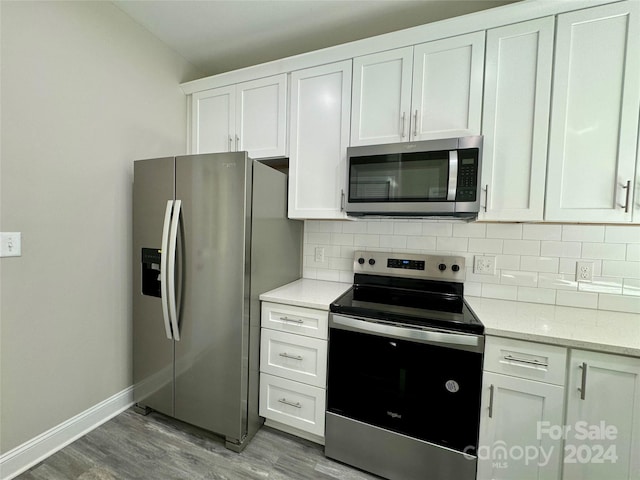 kitchen with light hardwood / wood-style floors, white cabinets, and stainless steel appliances