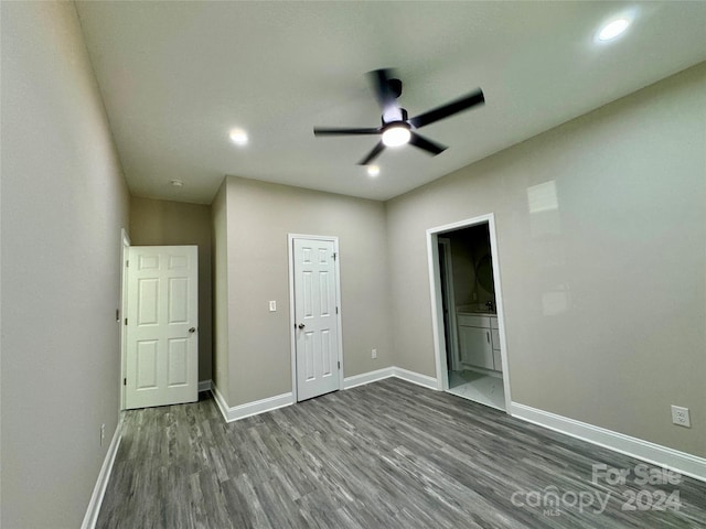 unfurnished bedroom featuring a closet, ensuite bathroom, wood-type flooring, and ceiling fan