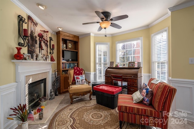 living area with ornamental molding, a high end fireplace, a healthy amount of sunlight, and ceiling fan