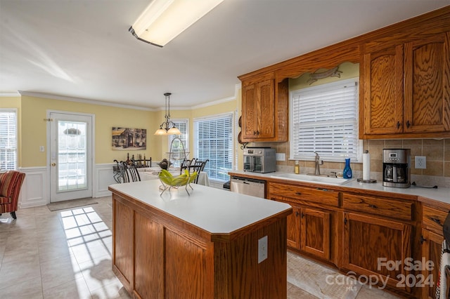 kitchen featuring tasteful backsplash, hanging light fixtures, stainless steel dishwasher, sink, and a center island