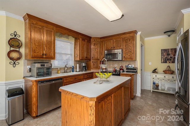 kitchen featuring sink, a kitchen island, backsplash, stainless steel appliances, and crown molding