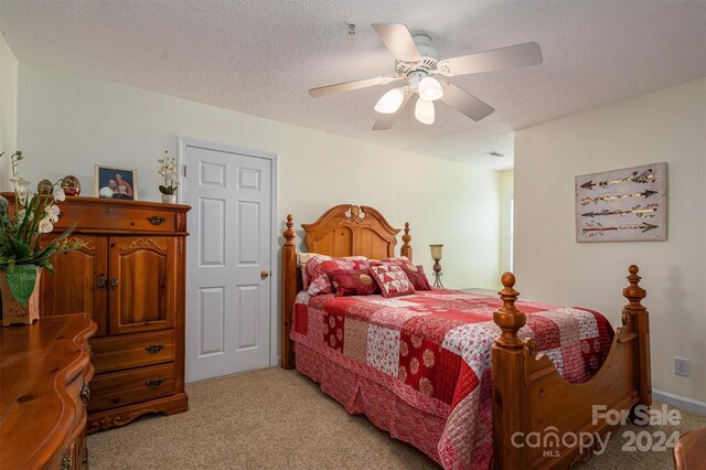 bedroom featuring a textured ceiling, light colored carpet, and ceiling fan