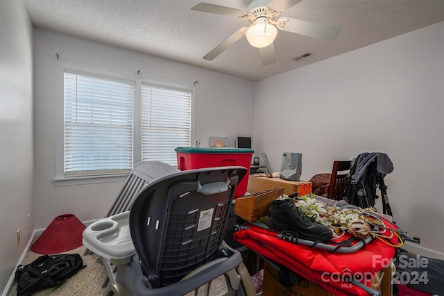 interior space with ceiling fan, carpet, and a textured ceiling