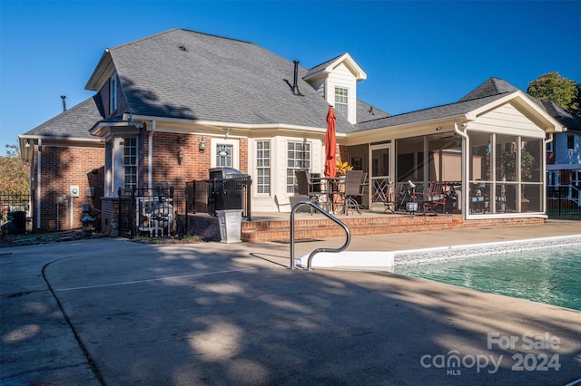 rear view of property featuring a fenced in pool, a patio area, and a sunroom