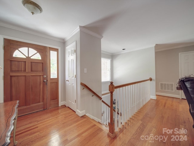 entrance foyer with a healthy amount of sunlight, ornamental molding, and light wood-type flooring