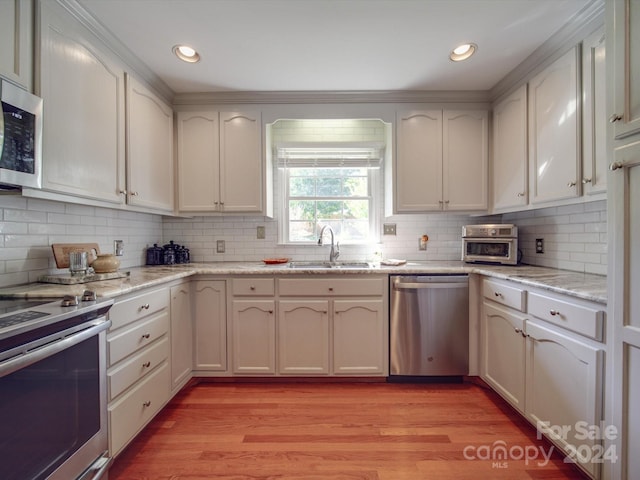 kitchen featuring sink, white cabinetry, stainless steel appliances, and light wood-type flooring