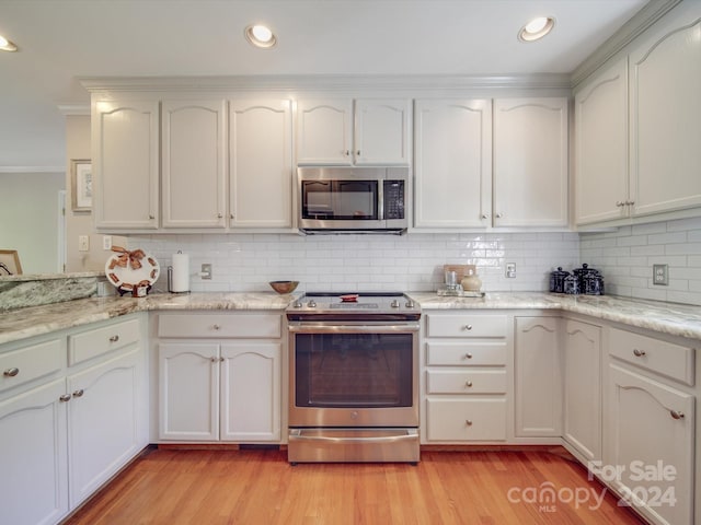 kitchen with light hardwood / wood-style floors, appliances with stainless steel finishes, decorative backsplash, and white cabinets