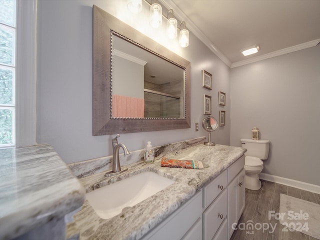 bathroom featuring a shower with shower door, toilet, vanity, hardwood / wood-style flooring, and ornamental molding