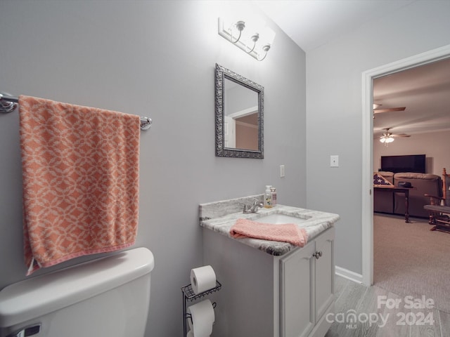 bathroom with toilet, vanity, and ceiling fan