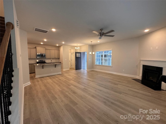 4049 Port Richmond Ave Unit 11, Gastonia, NC 28056 - unfurnished living room featuring recessed lighting, visible vents, ceiling fan with notable chandelier, a fireplace with flush hearth, and light wood-type flooring