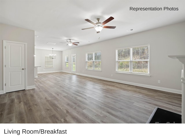 unfurnished living room featuring hardwood / wood-style floors and ceiling fan with notable chandelier