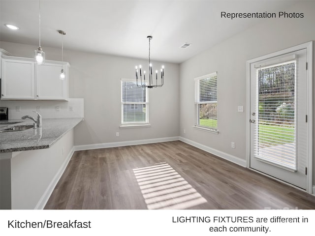 kitchen featuring sink, white cabinets, decorative light fixtures, and light wood-type flooring