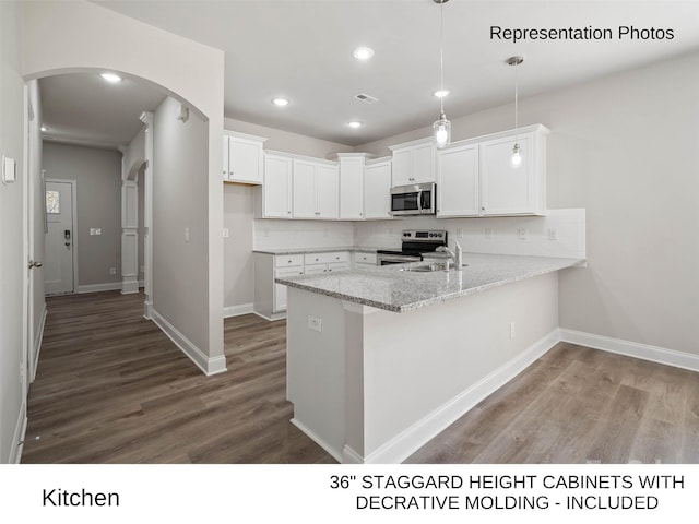 kitchen with wood-type flooring, stainless steel appliances, white cabinetry, and hanging light fixtures