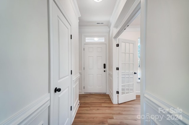 doorway to outside featuring light hardwood / wood-style floors and crown molding