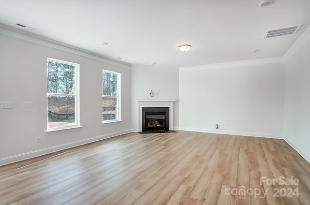 unfurnished living room with light hardwood / wood-style floors and crown molding