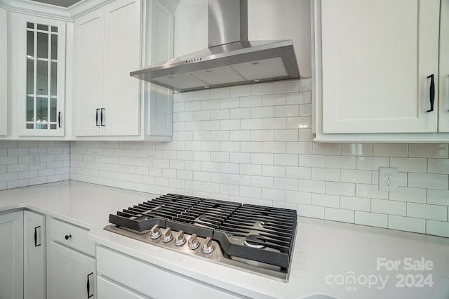 kitchen with backsplash, white cabinetry, stainless steel gas stovetop, and wall chimney exhaust hood