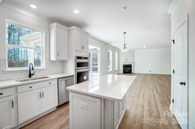 kitchen with sink, white cabinets, stainless steel appliances, and light hardwood / wood-style floors