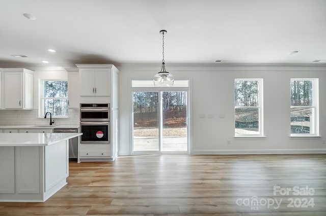 kitchen featuring a wealth of natural light, white cabinets, stainless steel appliances, and light hardwood / wood-style floors