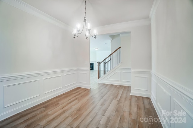 unfurnished dining area with a notable chandelier, light wood-type flooring, and ornamental molding