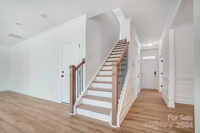 stairs featuring crown molding and hardwood / wood-style flooring