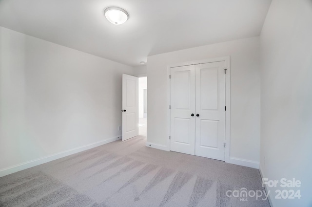 unfurnished bedroom featuring light carpet and a closet