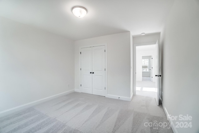 unfurnished bedroom with light colored carpet and a closet