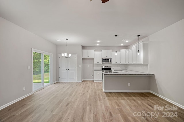 kitchen with kitchen peninsula, hanging light fixtures, light hardwood / wood-style flooring, white cabinetry, and stainless steel appliances