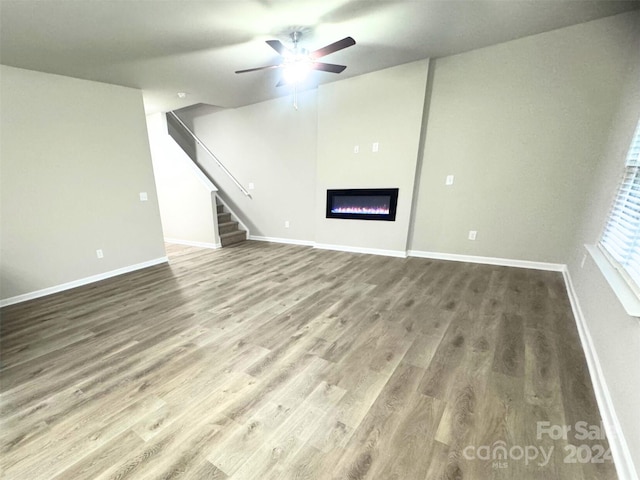 unfurnished living room with ceiling fan and wood-type flooring