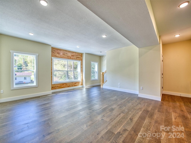 unfurnished living room featuring dark wood-type flooring and a textured ceiling