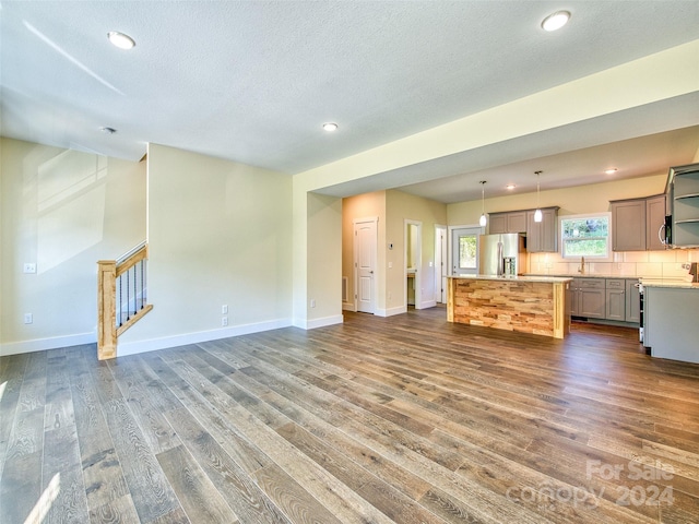 kitchen with a center island, stainless steel fridge with ice dispenser, hanging light fixtures, and dark hardwood / wood-style floors