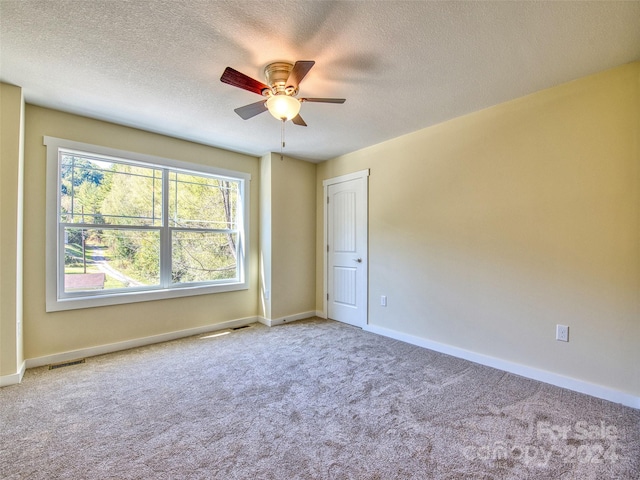 unfurnished room with a textured ceiling, carpet, and ceiling fan