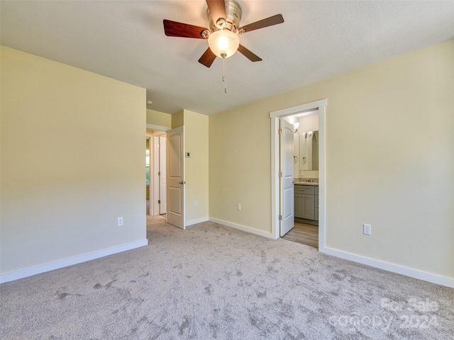 unfurnished bedroom featuring light carpet, ensuite bathroom, and ceiling fan