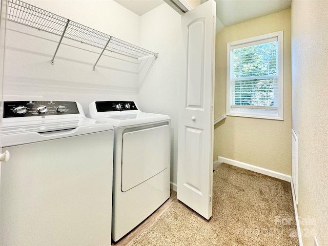 clothes washing area featuring washer and clothes dryer and light carpet