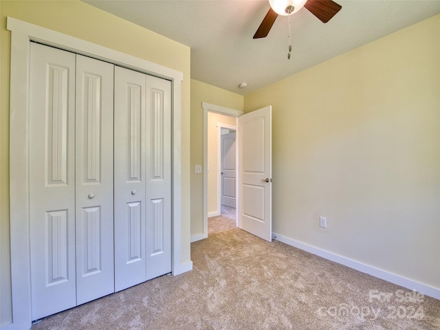 unfurnished bedroom with light colored carpet, a closet, and ceiling fan