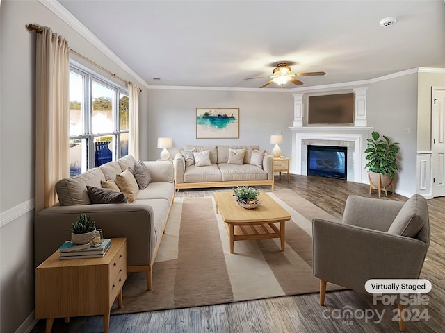 living room with hardwood / wood-style floors, a tiled fireplace, crown molding, and ceiling fan