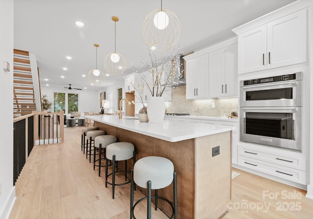 kitchen featuring pendant lighting, white cabinets, stainless steel appliances, a large island, and ceiling fan