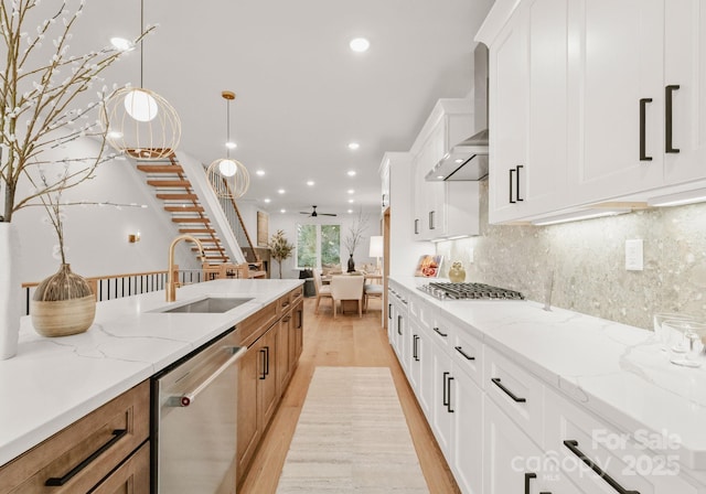 kitchen with light stone countertops, white cabinets, stainless steel appliances, sink, and hanging light fixtures