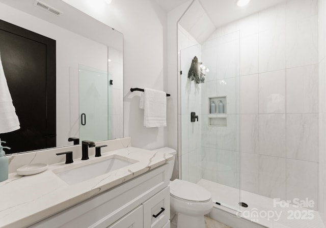 bathroom featuring toilet, a shower with shower door, and vanity